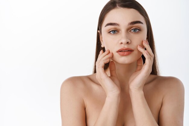 Visage de belle femme bouchent studio sur blanc. Heureuse belle fille tenant ses joues en regardant la caméra. Jolie femme nettoyer la peau fraîche. Expressions faciales expressives .Cosmétologie , beauté et Spa