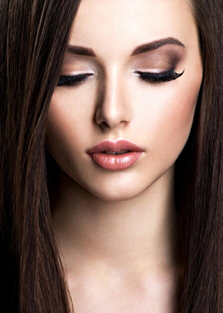 Visage de belle jeune femme avec maquillage brun et cheveux raides