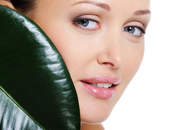 Visage de femme en bonne santé avec une feuille verte couvrir son visage de beauté