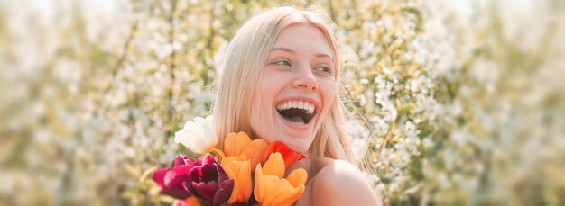 Visage de femme de printemps pour bannière. l'idée et le concept de femmes heureuses lors de la journée internationale de la femme. fille qui rit. fond de fleur de printemps.