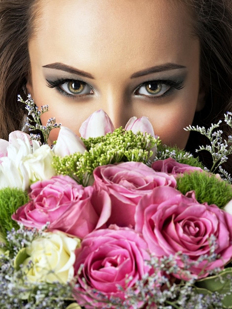 Visage gros plan de belle fille avec des fleurs. Jeune femme séduisante tient le bouquet de fleurs de printemps