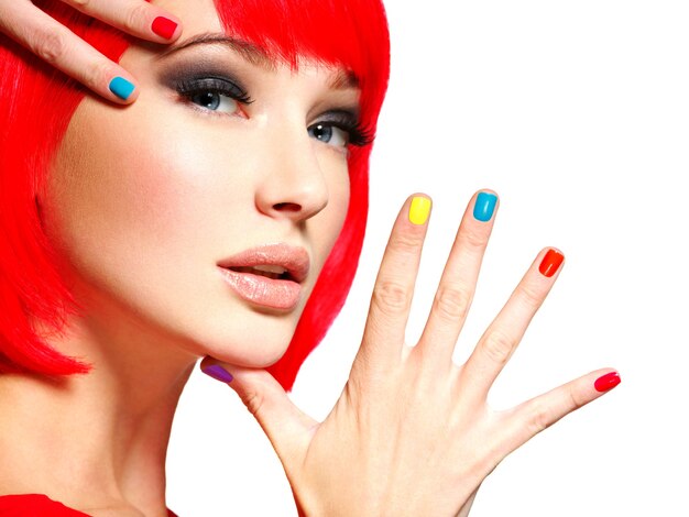 Visage gros plan d'une belle fille avec des ongles multicolores brillants.