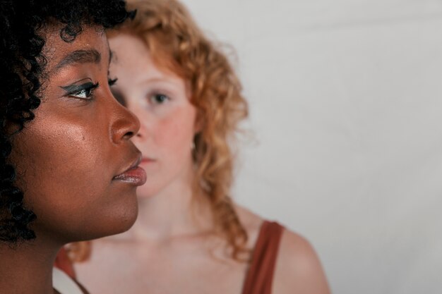 Le visage d&#39;une jeune femme africaine devant une femme blonde sur fond gris
