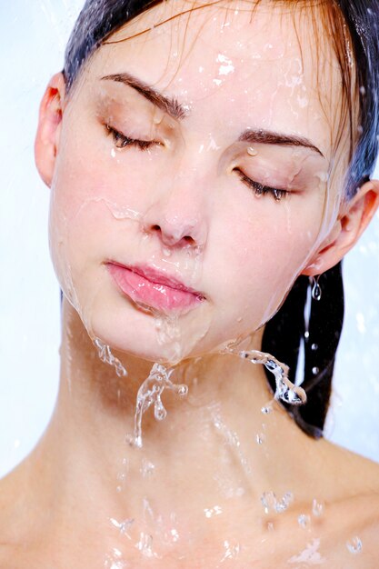 Visage de jeune femme avec jet d'eau sur son visage - traitement spa