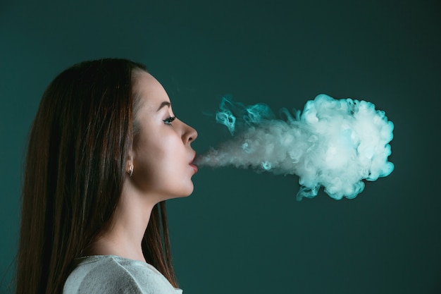 Photo gratuite le visage de la jeune femme vaping au studio noir