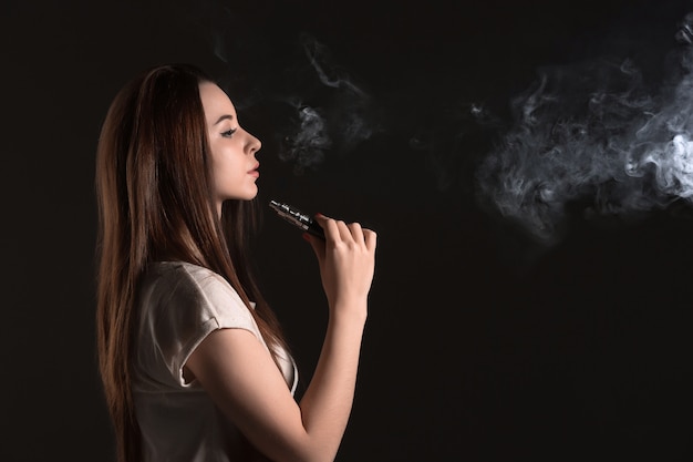 Photo gratuite le visage de la jeune femme vaping au studio noir