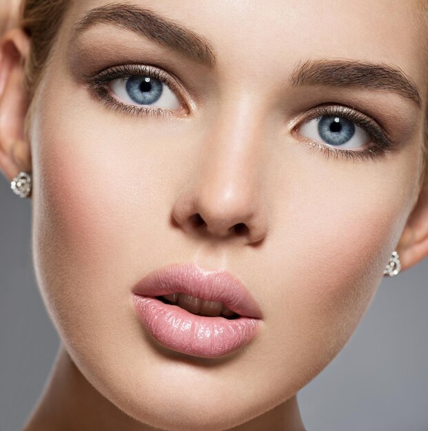 Visage d'une jolie fille magnifique aux yeux bleus sexy. Portrait d'une belle jeune femme avec du maquillage marron. Visage d'un mannequin aux yeux bleus.