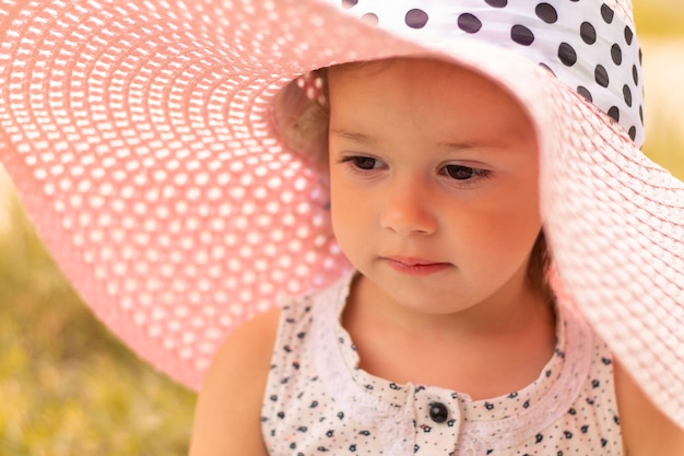 Visage d'une petite fille mignonne 1-3 dans un chapeau à larges bords d'été rose en été
