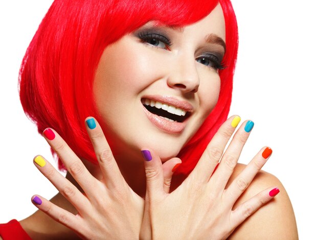 Visage surpris d'une jolie jeune femme aux cheveux rouge vif et aux ongles multicolores
