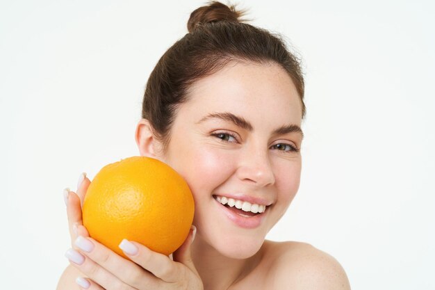 Vitamine C et concept de santé jeune beauté femme tenant un fruit d'orange près du visage concept d'organique