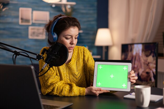 vlogger regardant un ordinateur portable et parlant d'une tablette avec un bureau à clé chroma