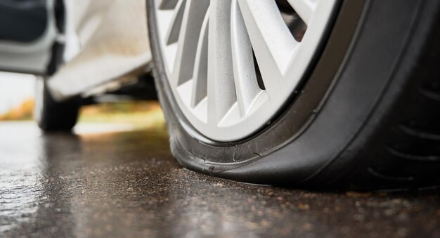 Voiture blanche arrêtée avec pneu crevé sur le bord de la route