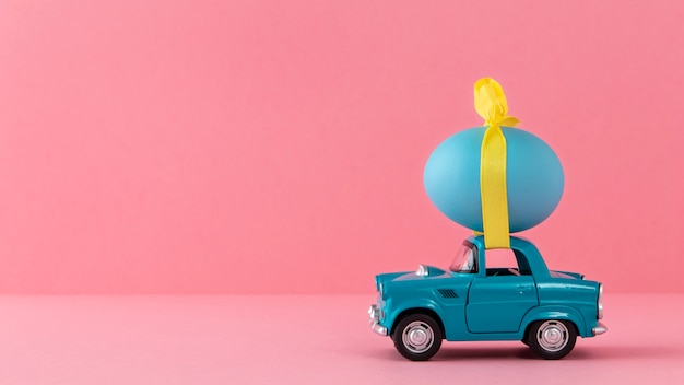 Photo gratuite voiture de pâques bleue avec oeuf bleu et ruban jaune