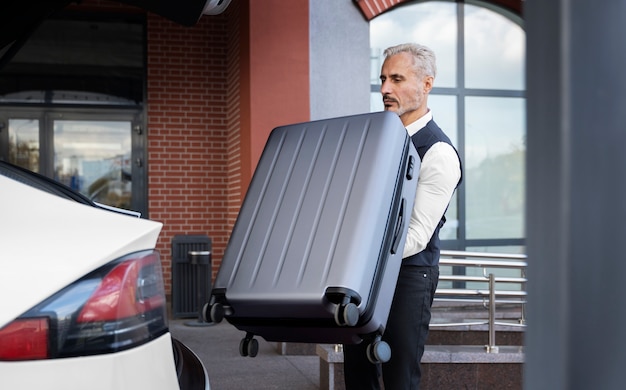 Photo gratuite voiturier tenant la vue de côté de bagages