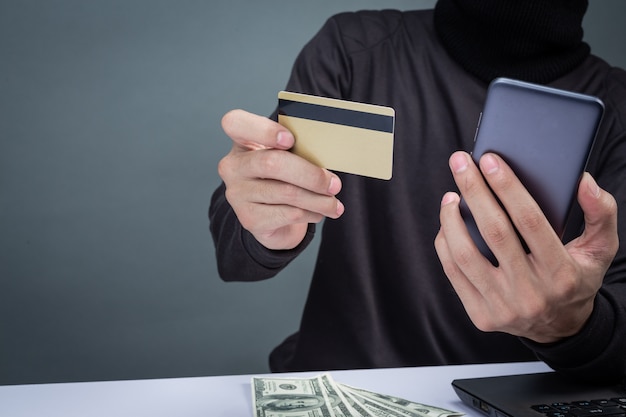 Photo gratuite les voleurs portent un chapeau noir, tenez le téléphone et une carte à puce en gris