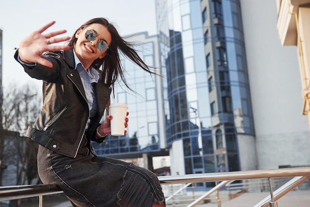 Vous pouvez voir le photographe dans le reflet des lunettes. Jeune belle fille dans des vêtements chauds se promène dans la ville à son heure du week-end