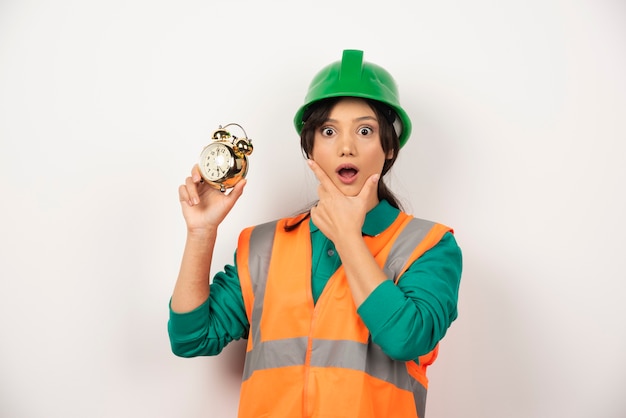 Photo gratuite vous vous demandez une employée avec un casque et tenant une horloge.