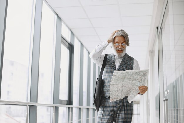 Voyage d'affaires. Concept d'entreprise et de personnes. Mâle en manteau gris. Senior avec une carte.