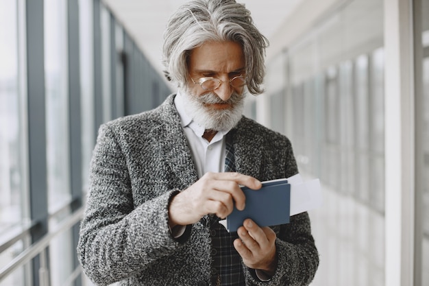 Voyage d'affaires. Concept d'entreprise et de personnes. Mâle en manteau gris. Senior avec un passeport.