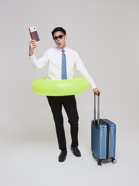 Voyage d'été homme d'affaires asiatique montrant un billet d'avion avec bagages et anneau gonflable de natation