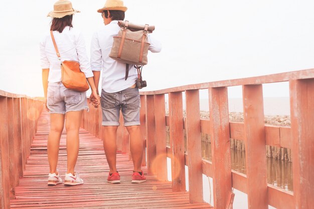 Un voyageur asiatique voyageant sur un pont de bois en bord de mer, concept Love and Travel