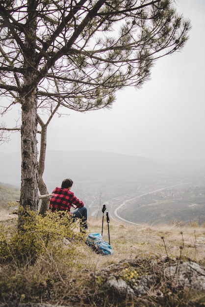 Photo gratuite voyageur assis à côté d'un arbre