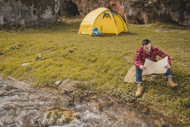 Voyageur avec une carte assise sur la pelouse