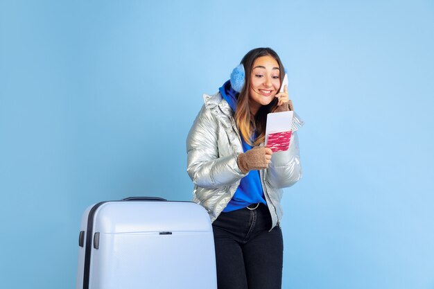 Voyageur. Portrait de femme caucasienne sur fond bleu studio. Beau modèle féminin dans des vêtements chauds. Concept d'émotions humaines, expression faciale, ventes, publicité. Humeur hivernale, période de Noël, vacances.