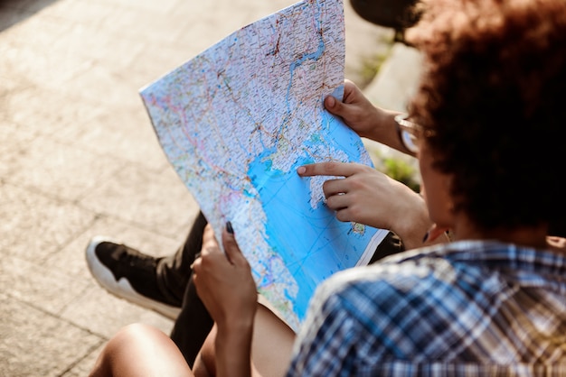 Voyageurs regardant l'itinéraire sur la carte, assis sur un banc dans le parc.