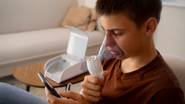 Vue d'un adolescent utilisant un nébuliseur à la maison pour des problèmes de santé respiratoire