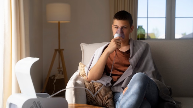 Vue d'un adolescent utilisant un nébuliseur à la maison pour des problèmes de santé respiratoire