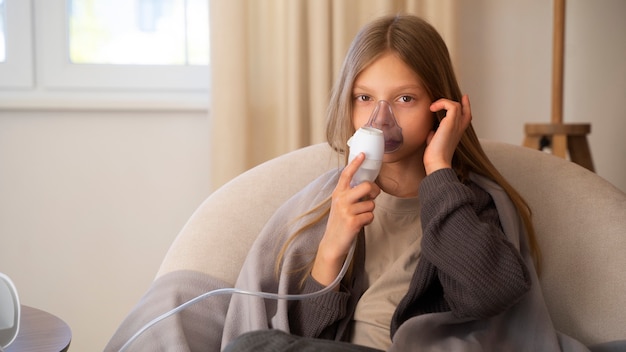 Vue d'une adolescente utilisant un nébuliseur à la maison pour des problèmes de santé respiratoire