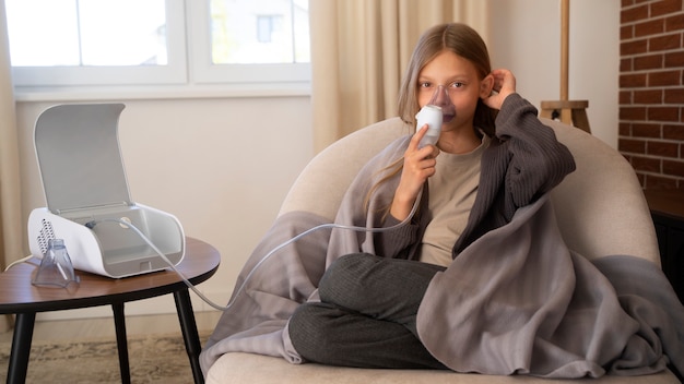 Photo gratuite vue d'une adolescente utilisant un nébuliseur à la maison pour des problèmes de santé respiratoire
