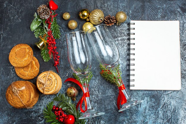 Vue aérienne d'accessoires de décoration de gobelets en verre biscuits empilés et cahier sur table sombre