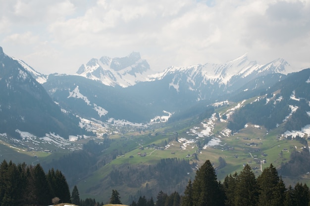 Vue aérienne d'une belle chaîne de montagnes recouverte de neige sous un ciel nuageux