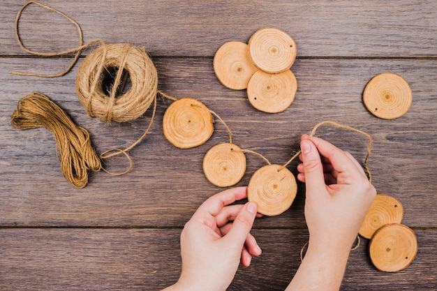 Vue aérienne de la bobine de jute faisant une guirlande avec des tranches de souche d'arbre sur un bureau en bois