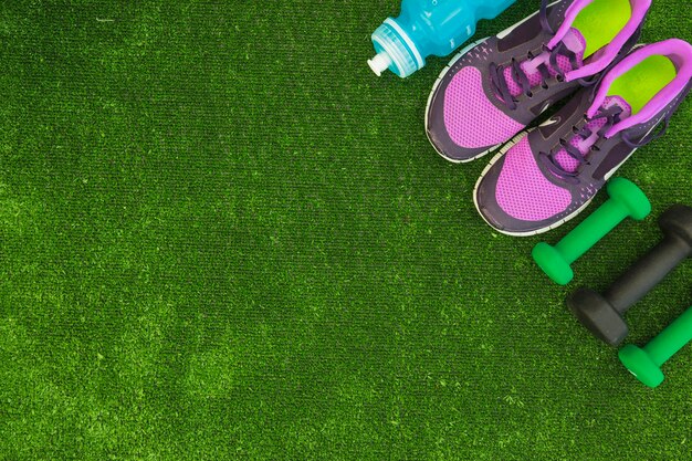 Une vue aérienne de la bouteille d&#39;eau; chaussures de sport et haltères sur gazon vert