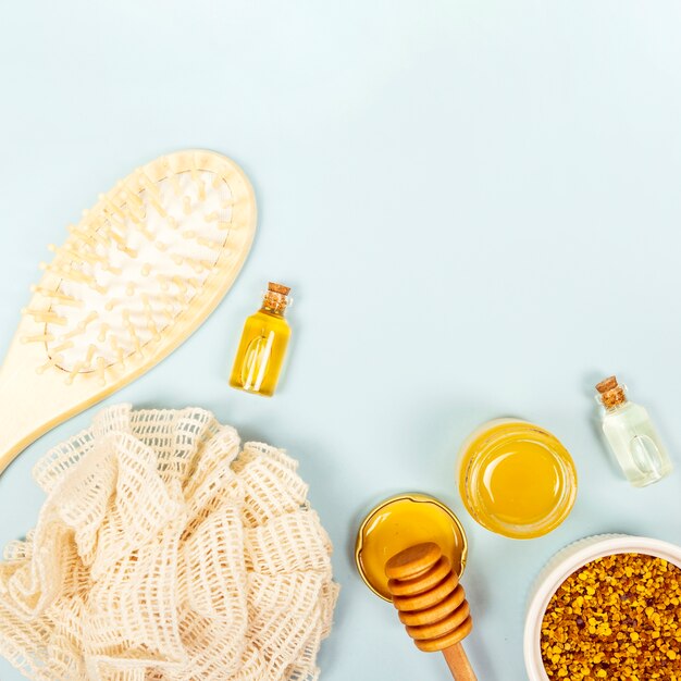 Vue aérienne de la brosse; bouteille d'huile essentielle; pot de miel; pollen d'abeille et loofah