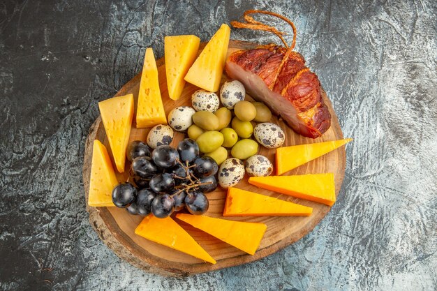 Vue aérienne d'une délicieuse collation comprenant des fruits et des aliments pour le vin sur un plateau marron sur fond gris