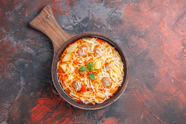 Vue aérienne d'une délicieuse soupe de nouilles au poulet sur une planche à découper en bois sur fond sombre image stock