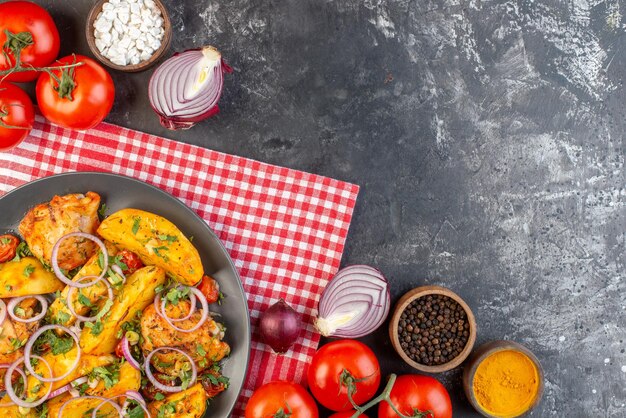 Vue aérienne d'un délicieux repas de poulet avec pommes de terre et légumes verts sur une serviette pliée rouge dépouillée de légumes épices sur une table de couleur sombre