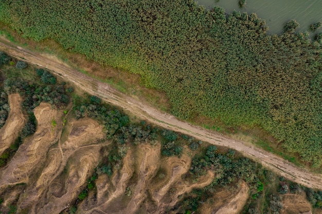 Vue aérienne de dessus de la route de campagne divisant les dunes de sable et de graminées.