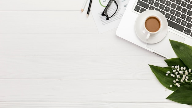 Vue aérienne du bloc-notes en spirale sur un ordinateur portable avec une tasse de café sur le bureau