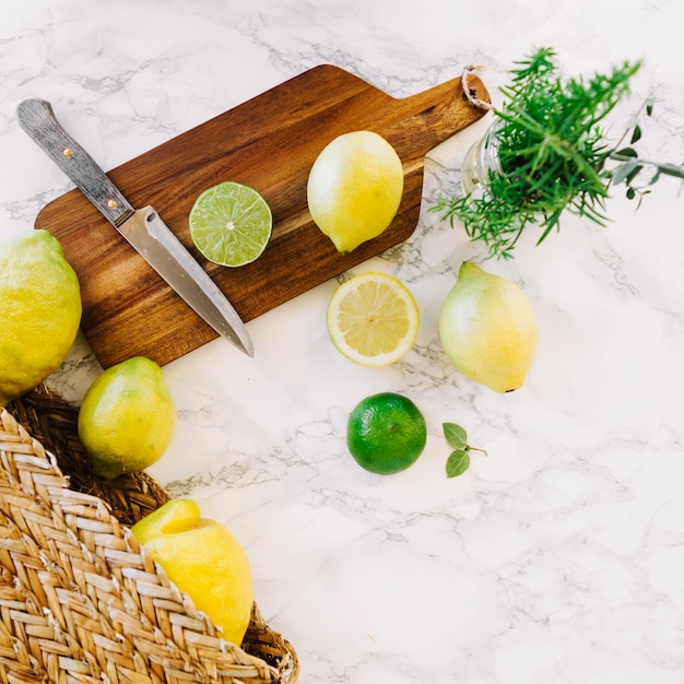 Photo gratuite vue aérienne du citron et du couteau sur une planche à découper en bois