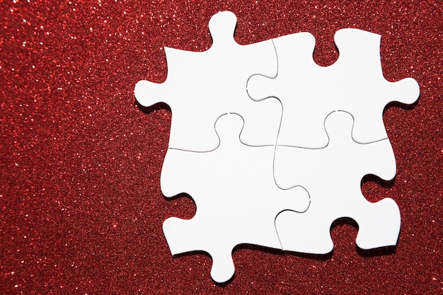 Vue aérienne du puzzle blanc sur fond de paillettes rouges
