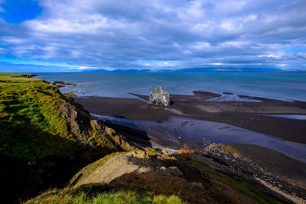 Photo gratuite vue aérienne du rivage près d'une colline herbeuse sous un ciel nuageux