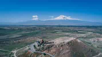 Photo gratuite vue aérienne d'une église arménienne sur une colline avec la montagne ararat et ciel bleu clair