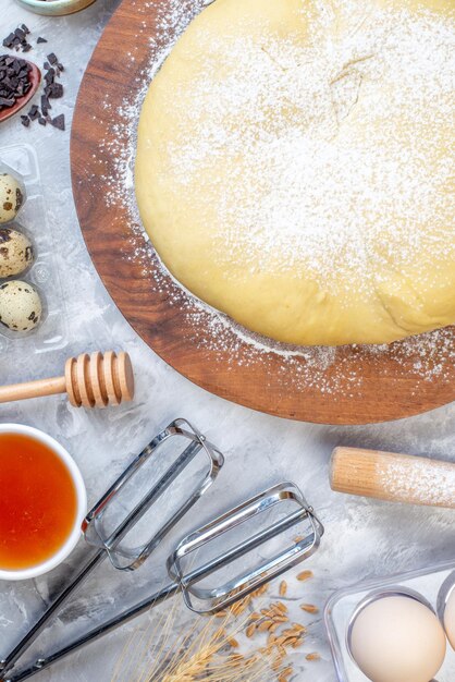 Vue aérienne de farine de pâtisserie crue sur des oeufs de miel de planche ronde sur fond blanc taché