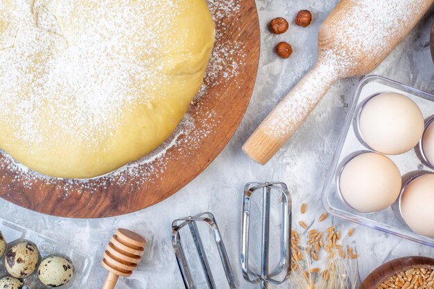 Vue aérienne de la farine de pâtisserie crue sur des œufs de râpe à planche ronde sur fond blanc taché