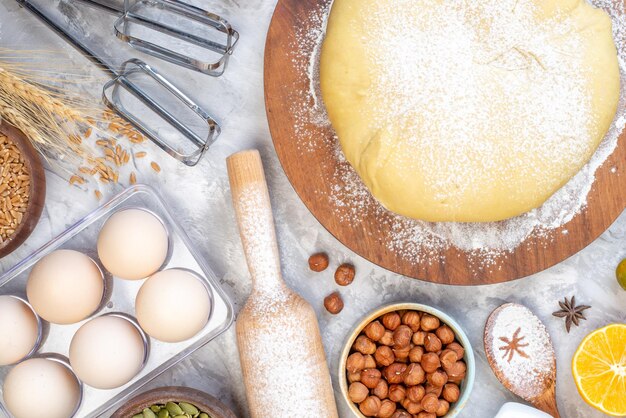 Vue aérienne de farine de pâtisserie crue sur planche ronde noisettes oeufs citron sur fond blanc taché